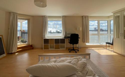 a living room with a bed and a room with windows at Very large ensuite room with wonderful view over the river Thames in a peaceful & calm residential building - SHARED flat with 1 host in London
