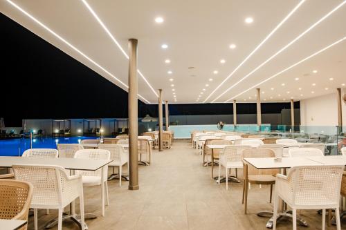 a restaurant with tables and chairs and a pool at Kapetanios Bay Hotel Protaras in Protaras