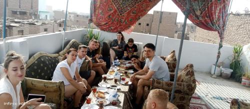 a group of people sitting around a table on a rooftop at Grand Hotel &Hostel in Luxor