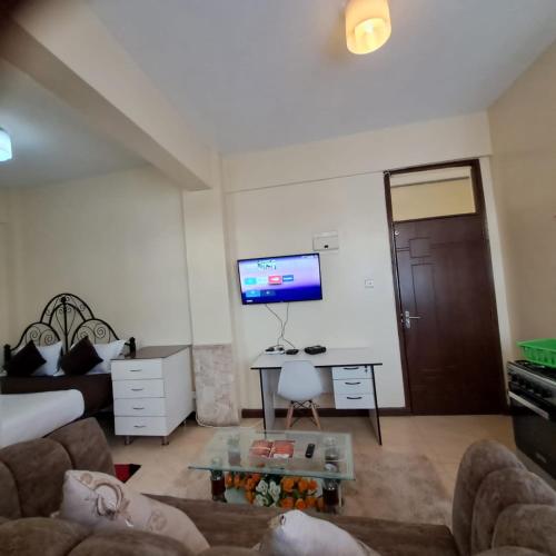 een woonkamer met een bank, een tafel en een tv bij Ngara - Emeli in Nairobi