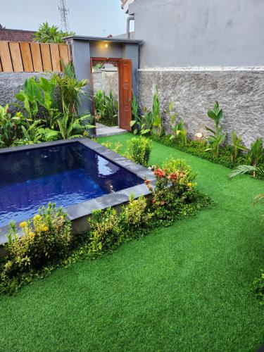 a swimming pool in the middle of a garden at THE JINENG,S SANUR in Sanur
