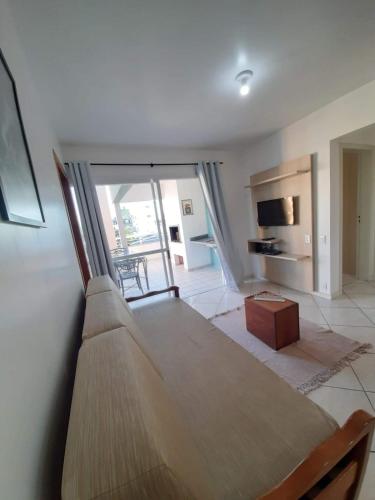 uma sala de estar com um sofá e uma mesa em Cobertura de dois dormitórios Summer Beach em Florianópolis