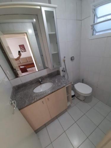 uma casa de banho com um lavatório, um WC e um espelho. em Cobertura de dois dormitórios Summer Beach em Florianópolis
