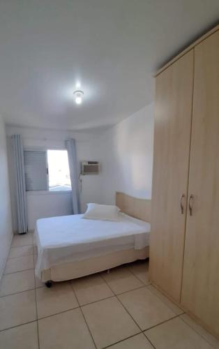 um quarto branco com uma cama e um armário em Cobertura de dois dormitórios Summer Beach em Florianópolis