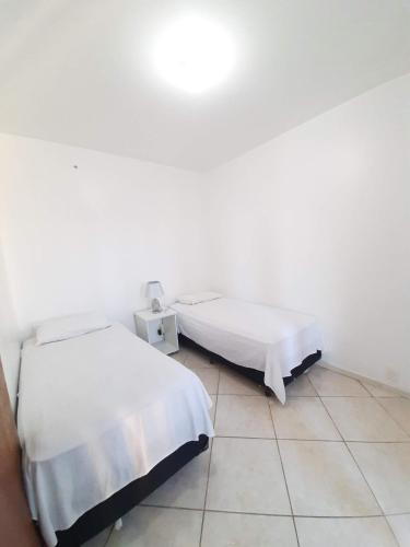 Duas camas num quarto com paredes brancas em Cobertura de dois dormitórios Summer Beach em Florianópolis