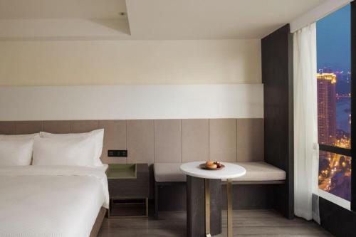 a hotel room with a bed and a small table at Jinxi Aerial Riverview Hotel - Chongqing Jiefangbei Hongya Cave in Chongqing