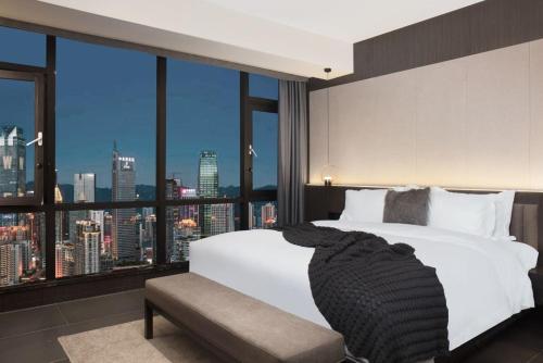 a bedroom with a white bed and a large window at Jinxi Aerial Riverview Hotel - Chongqing Jiefangbei Hongya Cave in Chongqing