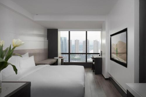 a hotel room with a white bed and a desk at Jinxi Aerial Riverview Hotel - Chongqing Jiefangbei Hongya Cave in Chongqing