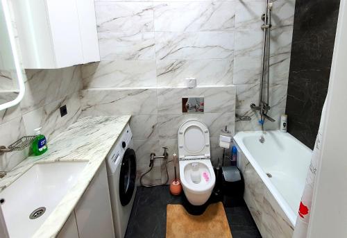 a bathroom with a toilet and a tub and a sink at Arbat apartment in the center city in Bishkek