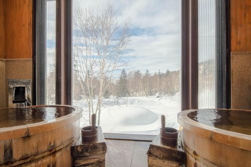 a room with a large window looking out at a snow covered yard at La Vista Daisetsuzan in Higashikawa