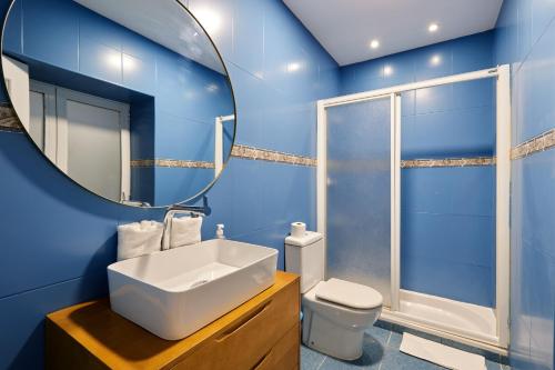 Baño azul con lavabo y espejo en TuApartamento Centro Ciudad Calle Caldereria 12, en Pamplona