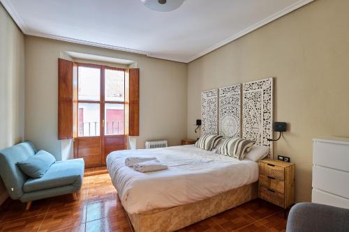 1 dormitorio con 1 cama grande y 1 silla azul en TuApartamento Centro Ciudad Calle Caldereria 12, en Pamplona