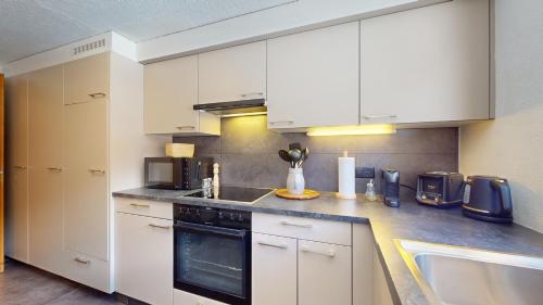 a kitchen with white cabinets and a sink at No 8 Bed & Bar in Verbier