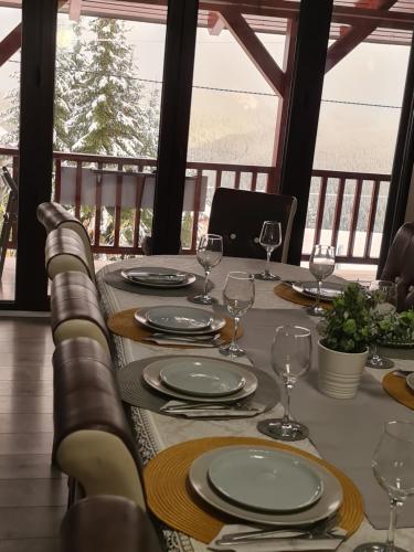 - une table avec des assiettes et des verres à vin sur une terrasse couverte dans l'établissement Cabana Sky High, à Rânca