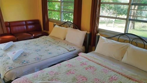 two beds in a room with a couch and windows at Viewsuay Farsai Wangnamkaew in Wang Nam Khieo