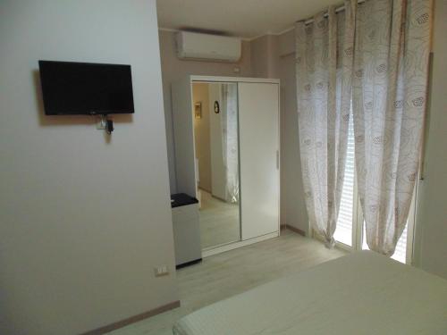 1 dormitorio con TV y puerta con espejo en Attico Del Sole en Rometta Marea