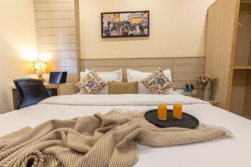 a bed with two glasses of orange juice on it at Perfectstayz Sagar Near Golden Temple in Amritsar