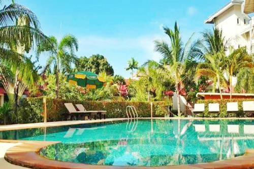 a swimming pool in a yard with palm trees at Dome Resort SHA Plus in Kata Beach