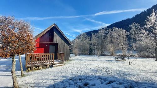 a red barn in a snow covered field with a bench at Chalets de la Wormsa in Metzeral