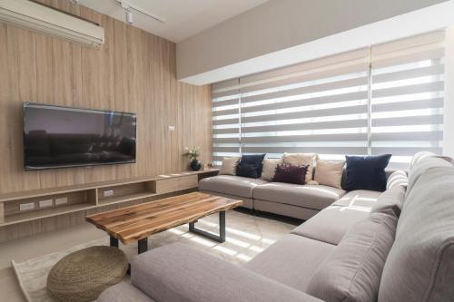 een woonkamer met een bank en een tv bij New Building Home 3B2b Daan Park MRT-2min 全新大樓家 3房2衛 2分到大安森林公園站 in Taipei