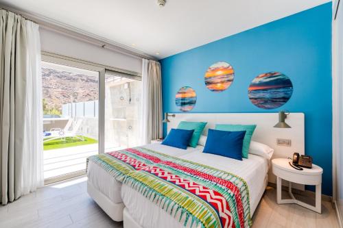 プエルト・デ・モガンにあるCordial Mogán Solazの青い壁のベッドルーム1室(大型ベッド1台付)