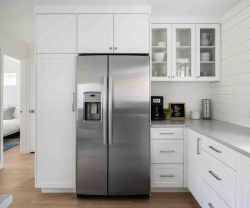 a stainless steel refrigerator in a kitchen with white cabinets at New Private West Coast Guesthouse on the creek in North Vancouver