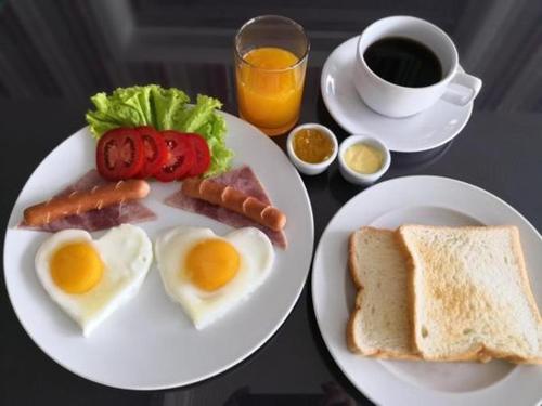 een tafel met twee borden eieren en worst en toast bij Lanta Andaleaf Bungalow - SHA Extra Plus in Koh Lanta