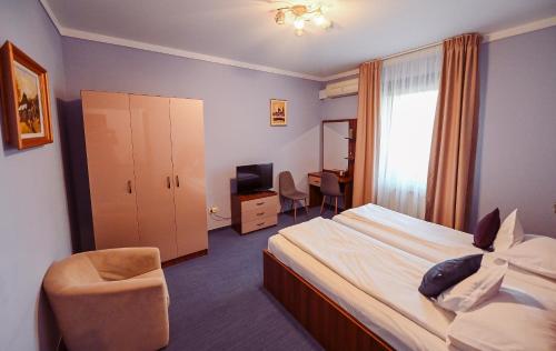 a hotel room with a bed and a chair and a desk at Conacul Domnesc in Suceava