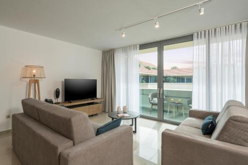 a living room with two chairs and a flat screen tv at Trianon Luxury Apartments & Suites in Chania Town