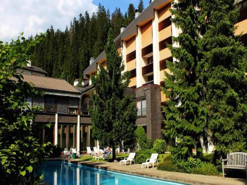 a hotel with a swimming pool in front of a building at Laax Rancho Studio Apartment in Laax