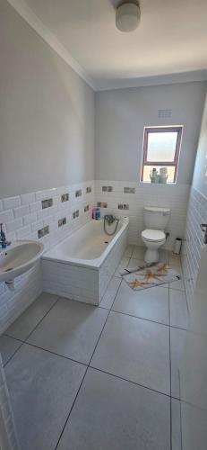 a white bathroom with a tub and a toilet at Quaint Family home, walking distance to the beach in Cape Town