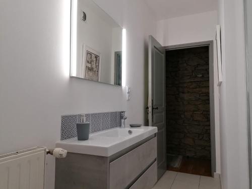 uma casa de banho branca com um lavatório e um espelho em Le Sainte Catherine - Appt centre-historique em Dinan