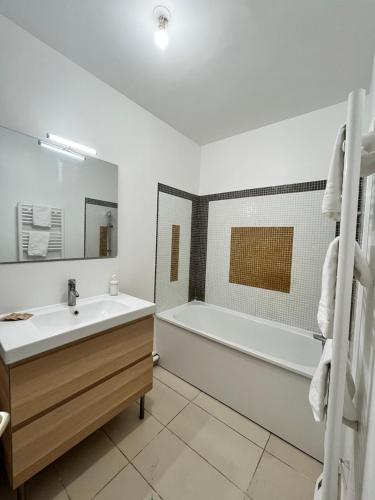 ein Badezimmer mit einer weißen Badewanne, einem Waschbecken und einem Badetubermott in der Unterkunft Maison Paisible à 15 min de Disneyland ! in Crégy-lès-Meaux