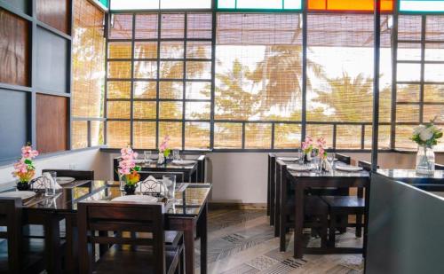 a restaurant with tables and chairs and a large window at Namastay Leisure Homes in Kovalam