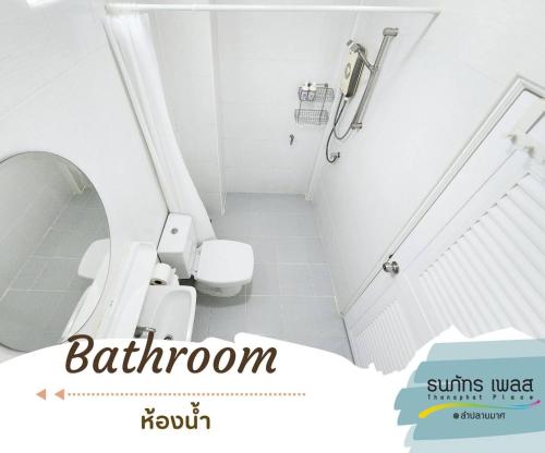 a white bathroom with a toilet and a shower at Thanaphat place in Buriram