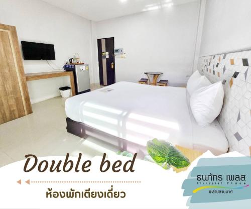 1 dormitorio con 1 cama blanca grande y TV en Thanaphat place, en Buriram