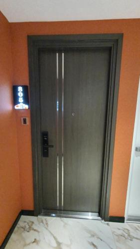 a metal door in a room with an orange wall at MOMIZI HANOI 2 - PHAN KE BINH in Hanoi