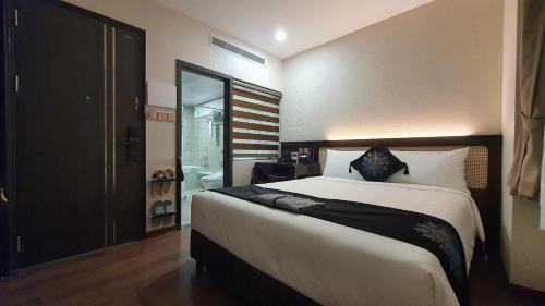 a bedroom with a large bed and a bathroom at MOMIZI HANOI 2 - PHAN KE BINH in Hanoi