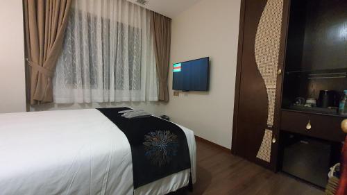 a hotel room with a bed and a flat screen tv at MOMIZI HANOI 2 - PHAN KE BINH in Hanoi