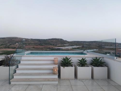 a view from the balcony of a house with stairs and plants at Panorama Lounge - Romantic Getaway with private pool in Mġarr