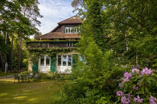 une maison ancienne avec une table et des chaises dans un jardin dans l'établissement Haus Hubertus - die Strandvilla, à Boltenhagen