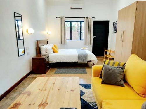 ein Schlafzimmer mit einem Bett und einem gelben Sofa in der Unterkunft Instahomes by Tru - Mt Pleasant Apartments in Blantyre