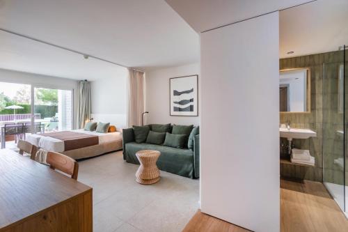 sala de estar con sofá verde y cama en Cabot Las Velas Apartments, en Puerto Pollensa