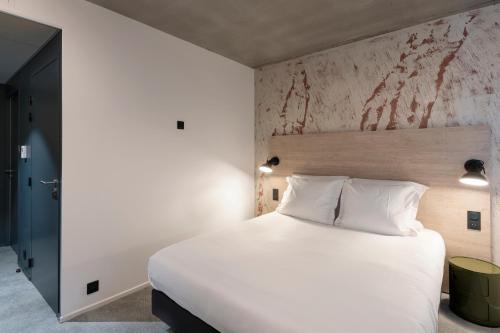 a bedroom with a large white bed and a wall at Quai Central in Tourcoing