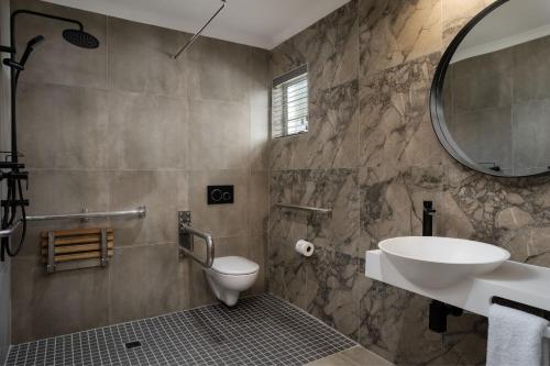 a bathroom with a sink and a toilet and a mirror at Protea Hotel by Marriott Walvis Bay Indongo in Walvis Bay