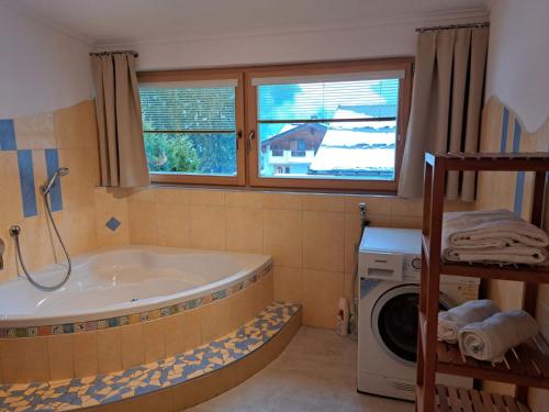 a bathroom with a tub and a washing machine at Edelweiss Apartments 200m zum Lift - Silvretta Card Premium Inklusive in See
