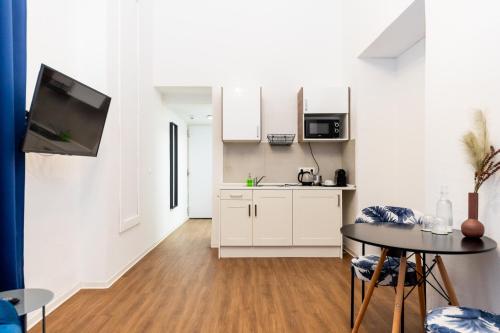 a kitchen with white cabinets and a table in a room at Adagio Downtown Rooms in Budapest