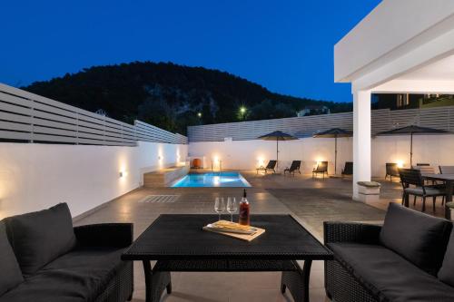 a patio with a table and chairs and a pool at Olea Villa in Archipolis