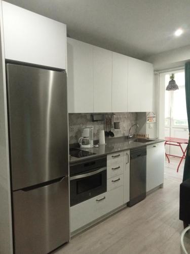 a kitchen with a stainless steel refrigerator and white cabinets at Estudio independiente Forget Me Not in Getxo