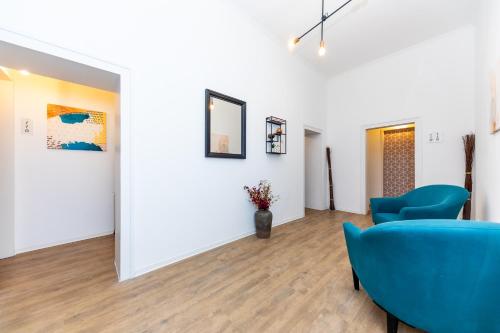 a room with blue chairs and paintings on the wall at Adagio Downtown Rooms in Budapest